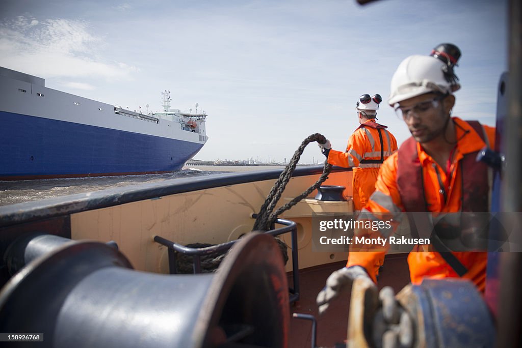 Tug workers with rope on tug at sea