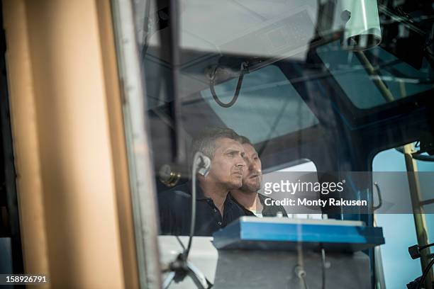 captain and mate steering tug, view through window - boat captain stockfoto's en -beelden