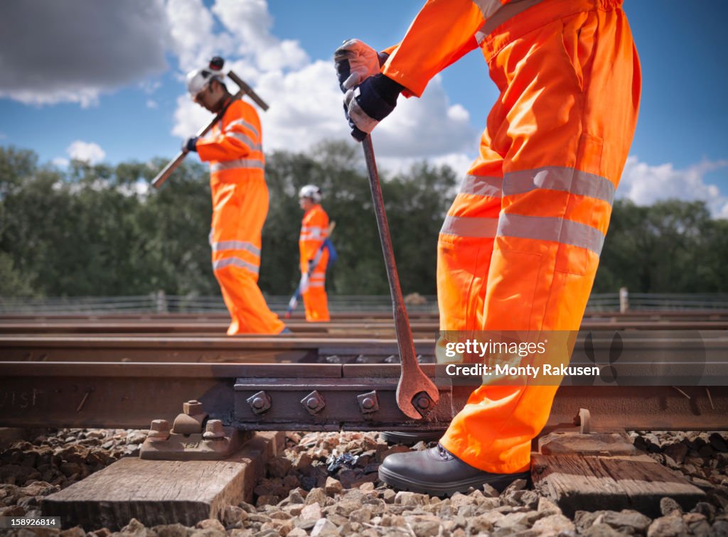 Railway workers wearing high visibility clothing repairing railway track side view