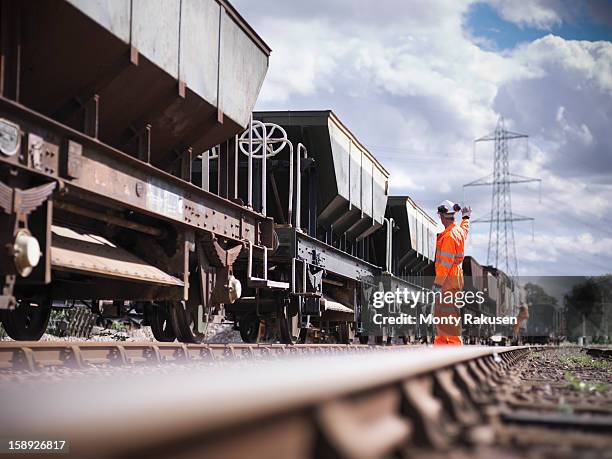 railway worker wearing high visibility clothing waving alongside train - rail stock pictures, royalty-free photos & images