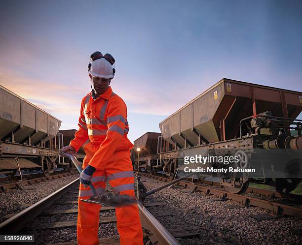 railway worker with spade working on railway tracks at night - rail transportation stock pictures, royalty-free photos & images
