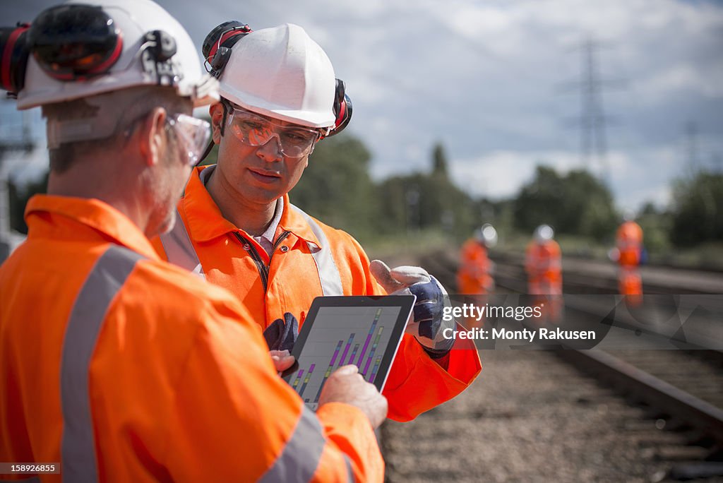 Railway workers using digital tablet to discuss work