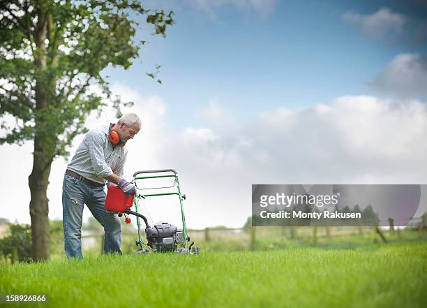 gardener pouring petrol into lawn mower - gasoline pouring stock pictures, royalty-free photos & images