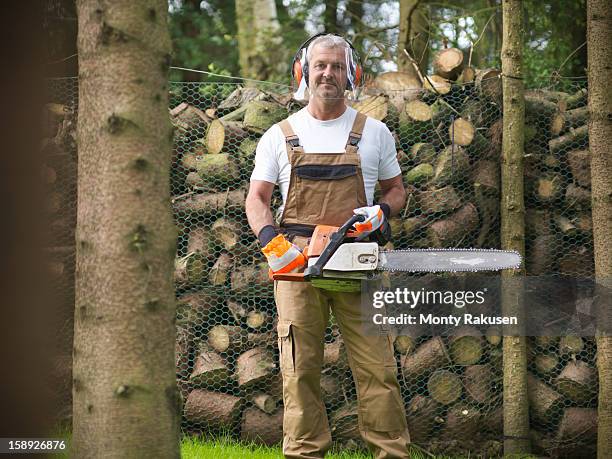 portrait of man wearing ear protectors and visor holding chainsaw - chainsaw stock pictures, royalty-free photos & images
