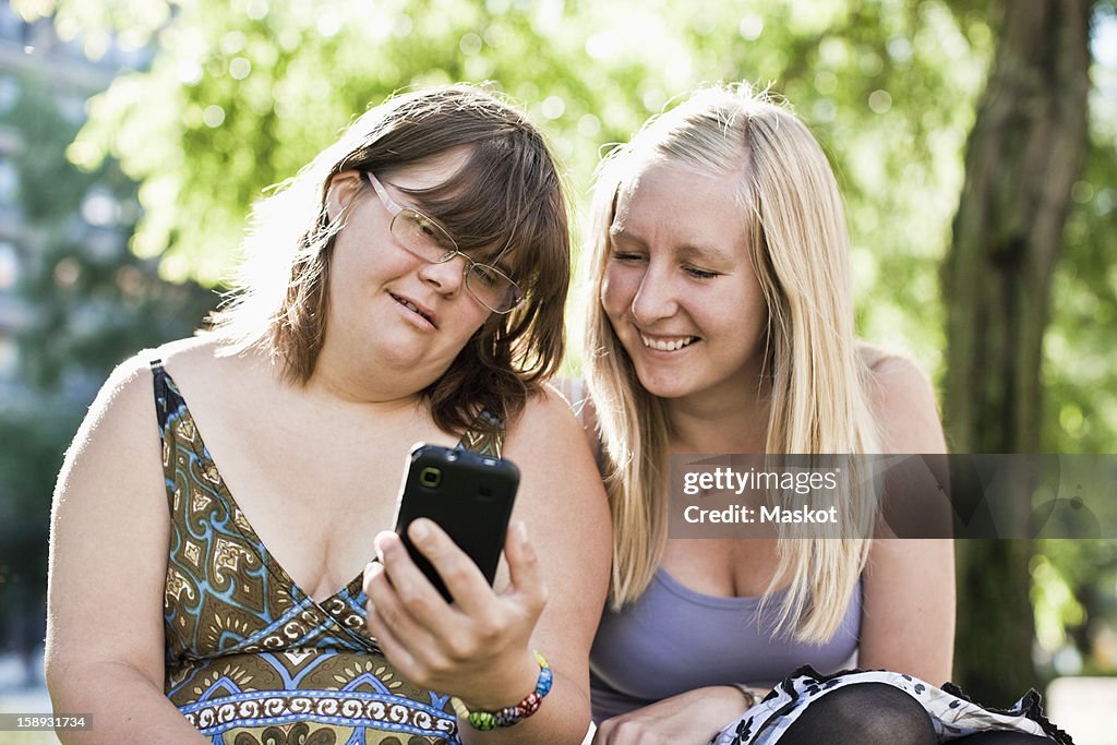 Young woman with down syndrome her personal assistant looking at phone together