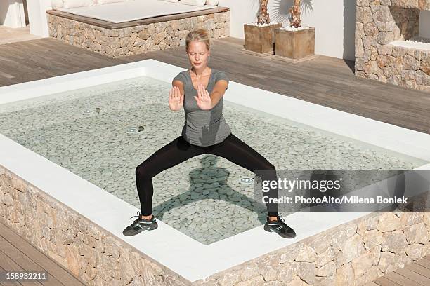 young woman practicing tai chi chuan in patio with eyes closed - tai chi shadow stock pictures, royalty-free photos & images