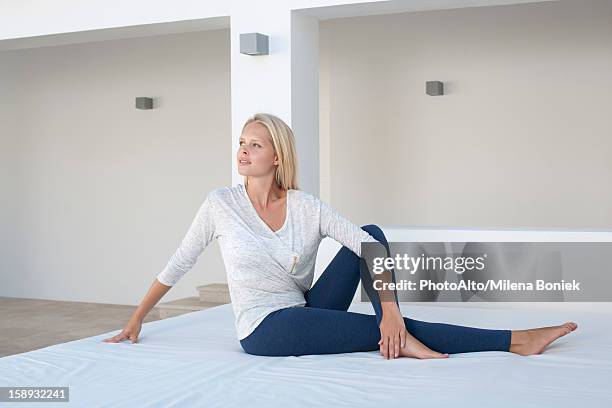 young woman doing spinal twist yoga pose on bed outdoors - spinal twist stock pictures, royalty-free photos & images