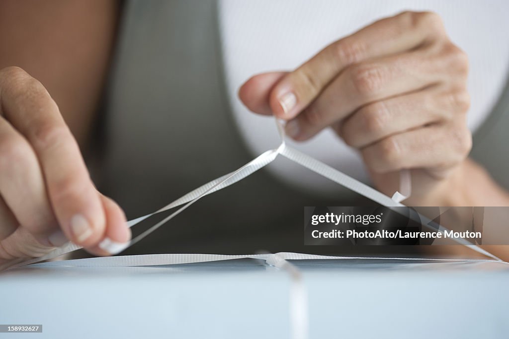 Woman tying ribbon on present