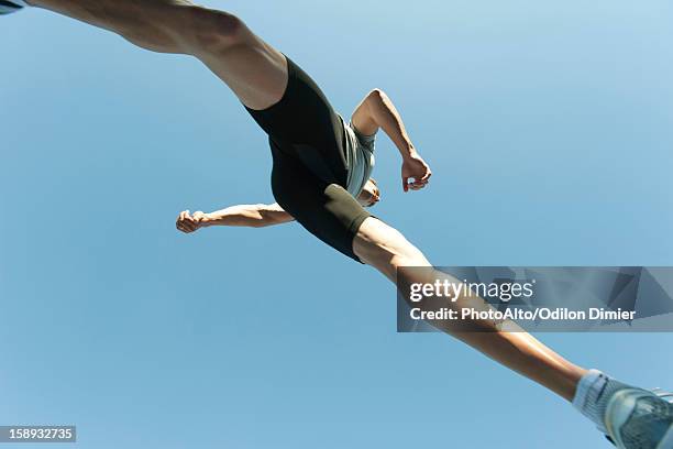 man jumping in air, directly below - running shoes sky stock-fotos und bilder