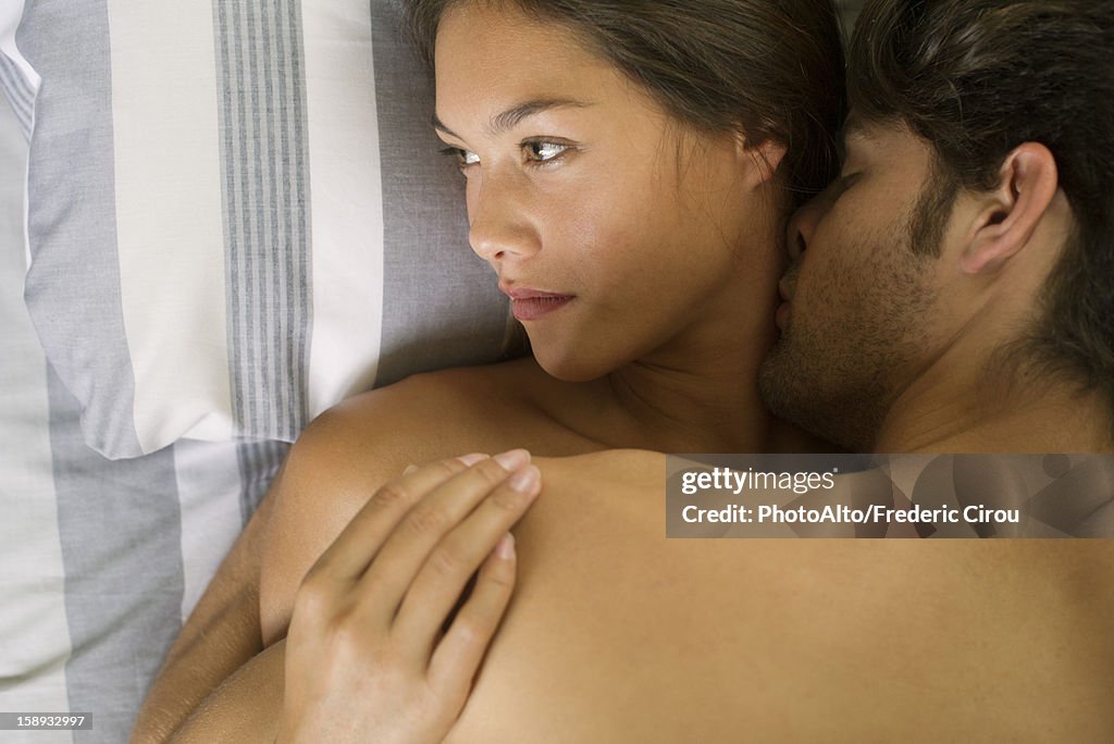 Young couple being intimate in bed, woman looking away