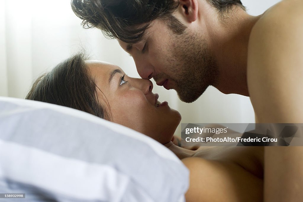 Young couple romancing in bed, side view