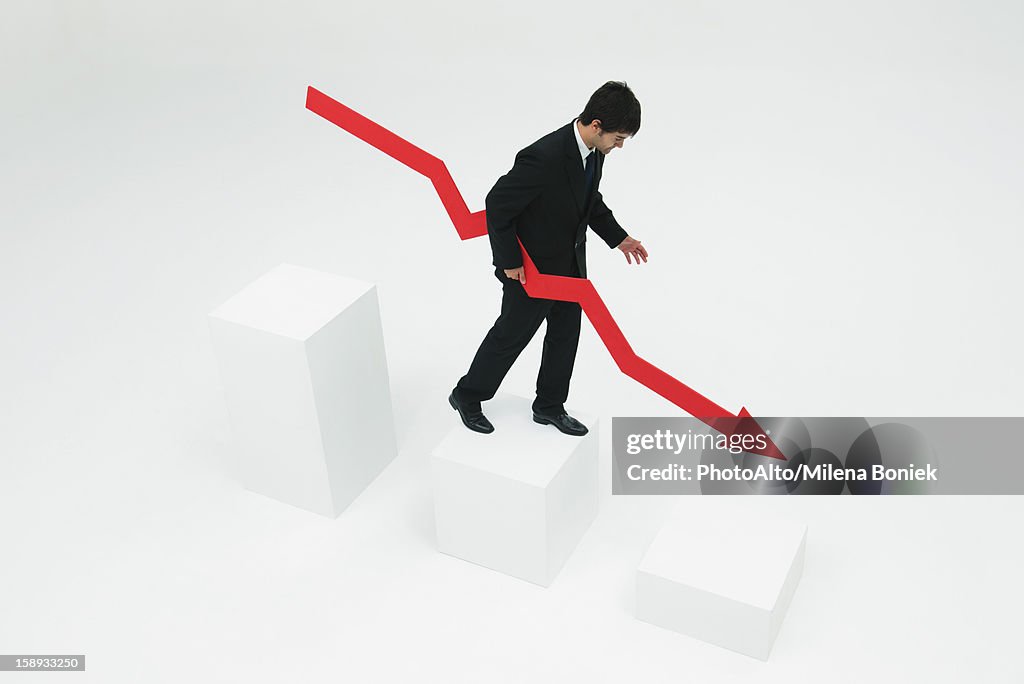 Businessman descending steps holding arrow pointed downward
