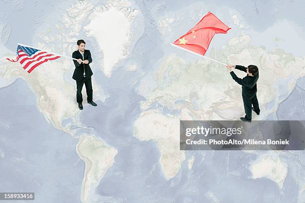 businessmen standing on world map, waving american and chinese flags - chinese american stockfoto's en -beelden
