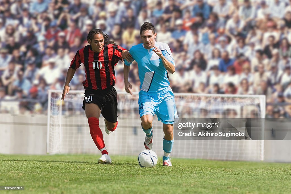 Two soccer players challenging for the ball