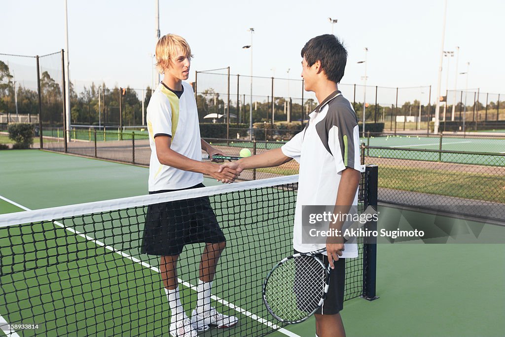 Two tennis players shaking hands at net