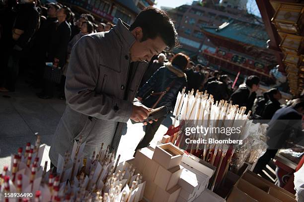 Man buys a decorative arrow - a charm for warding off bad luck - on the first day of business in 2013 at the Kanda Myojin shrine in Tokyo, Japan, on...