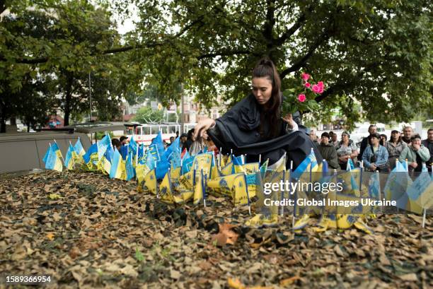 Wife of a fallen soldier places a memorial flag and lays flowers at the Memorial during a commemorative action on the Day of Ukrainian Statehood on...