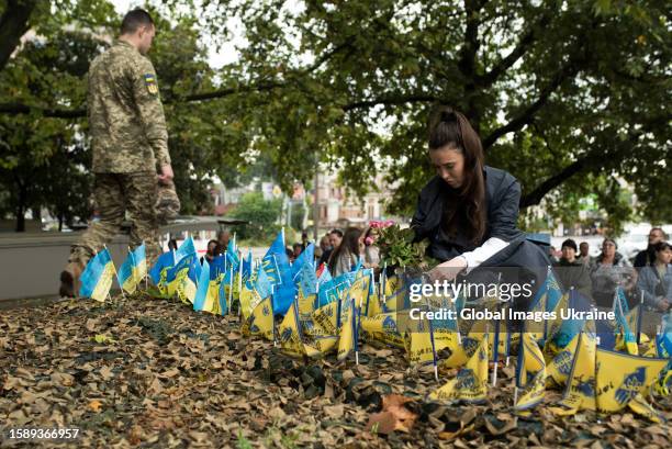 Wife of a fallen soldier places a memorial flag and lays flowers at the Memorial during a commemorative action on the Day of Ukrainian Statehood on...