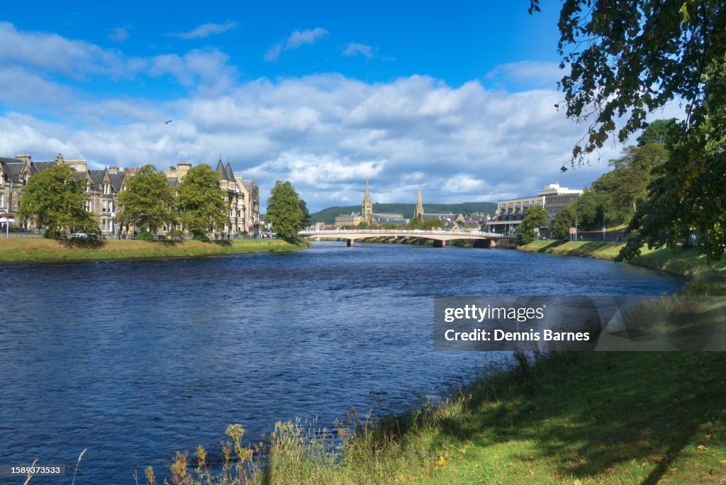 Looking north up tree lined footpath beside River ness (towards city centre) and Ness Bridge near the centre of Invernes city.