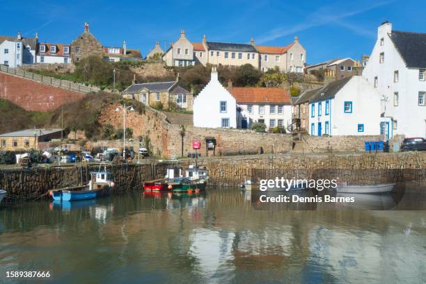 looking west across ancient crail harbour to ancient houses on quayside and small boats in harbour.      neuk of fife, scotland uk - río del este fotografías e imágenes de stock