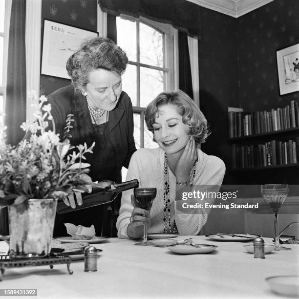 British model Sandra Paul has her wine glass filled by a woman named as Helen Burke, March 17th 1959.