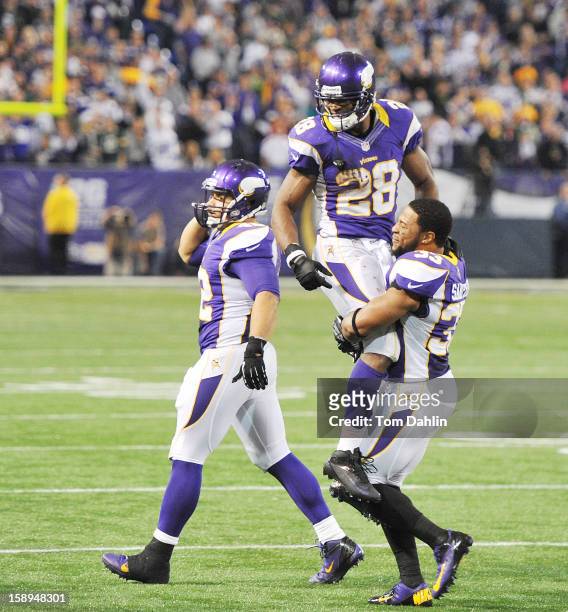 Adrian Peterson of the Minnesota Vikings is carried off the field by teammates Jamarca Sanford and Jerome Felton during an NFL game against the Green...