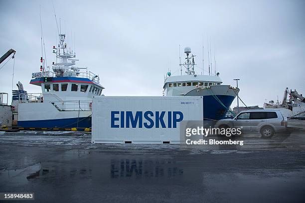 The logo of Eimskipafelag Island hf, or Eimskip, shipping and storage company sits on a container next to commercial fishing vessels at the harbor in...