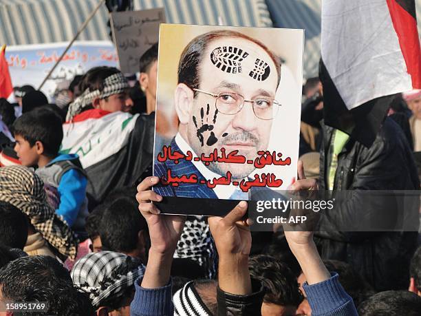 Iraqi Sunni protestors hold up a portrait of Prime Minister Nuri al-Maliki with slogans reading in Arabic, "liar...sectarian, thief, collaborator"...