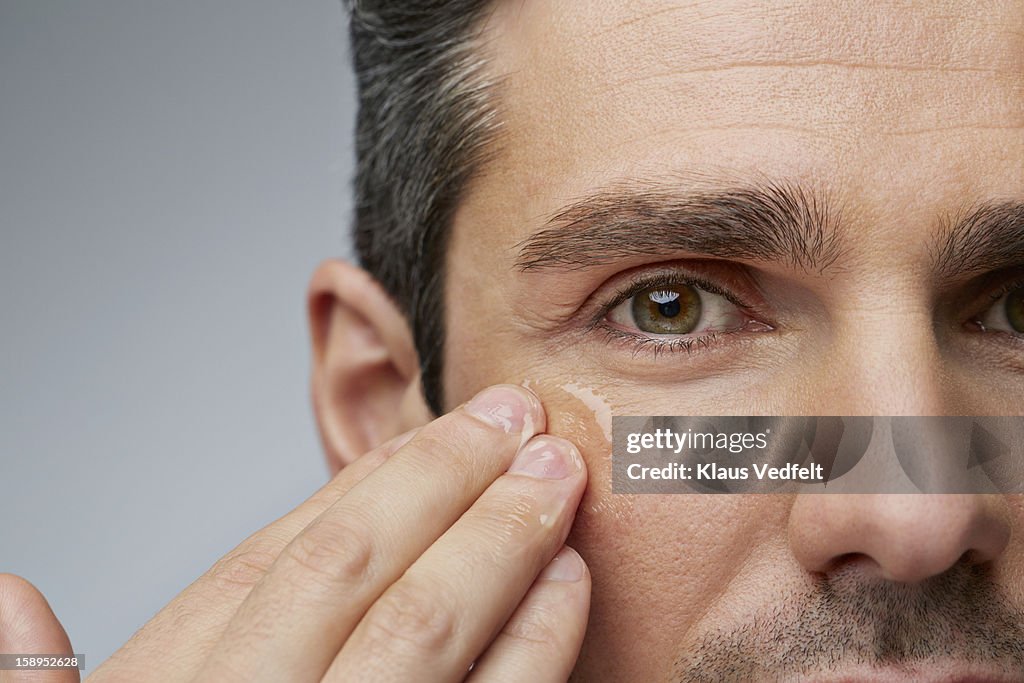 Man putting anti wrinkle gel around the eyes