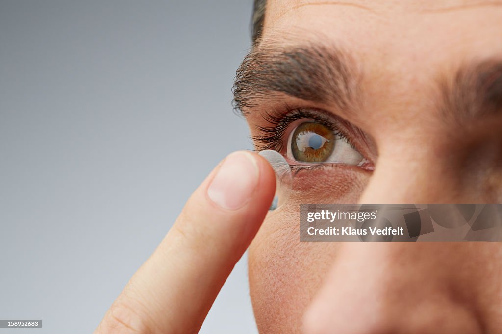 Close up of man putting in contact lens