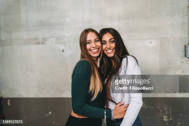 porträt zweier freunde, die sich gemeinsam an einer alten wand umarmen - südeuropäischer abstammung stock-fotos und bilder