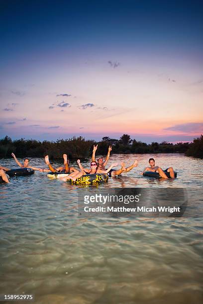 travelers relax in tubes and take in the sunset - river mekong stockfoto's en -beelden