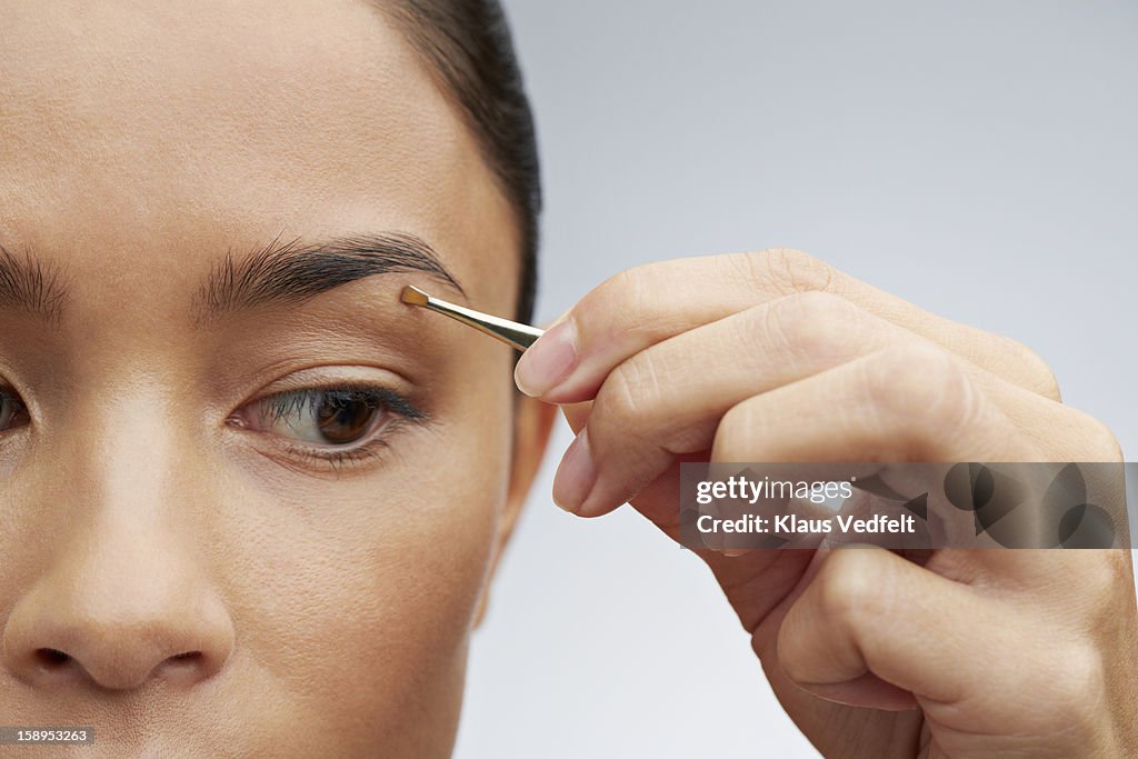 Close-up of woman plucking her eyebrows