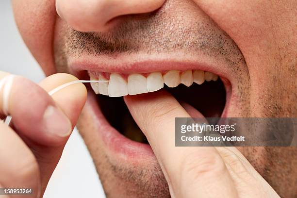 close-up of man cleaning teeth with dental floss - dental floss stock pictures, royalty-free photos & images