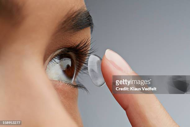 close-up of woman putting in contact lens - lente de contacto imagens e fotografias de stock
