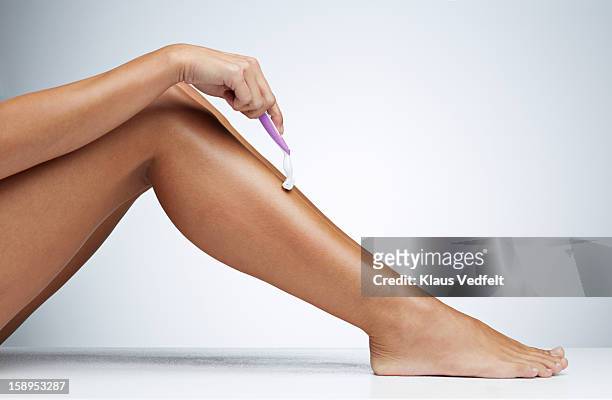 close-up of woman shaving her leg - shaved stockfoto's en -beelden