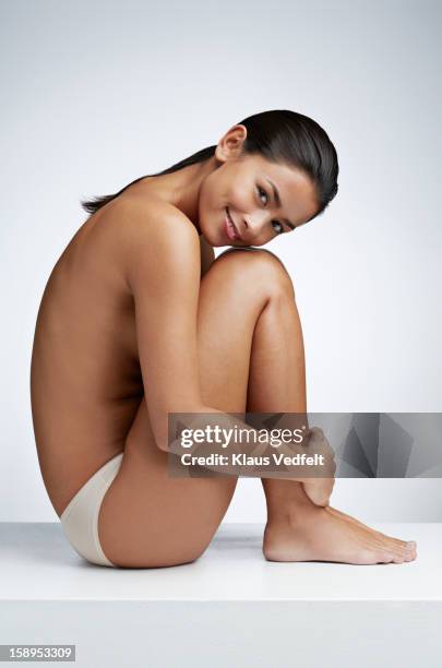 woman sitting half naked smiling, white background - hugging knees stock pictures, royalty-free photos & images