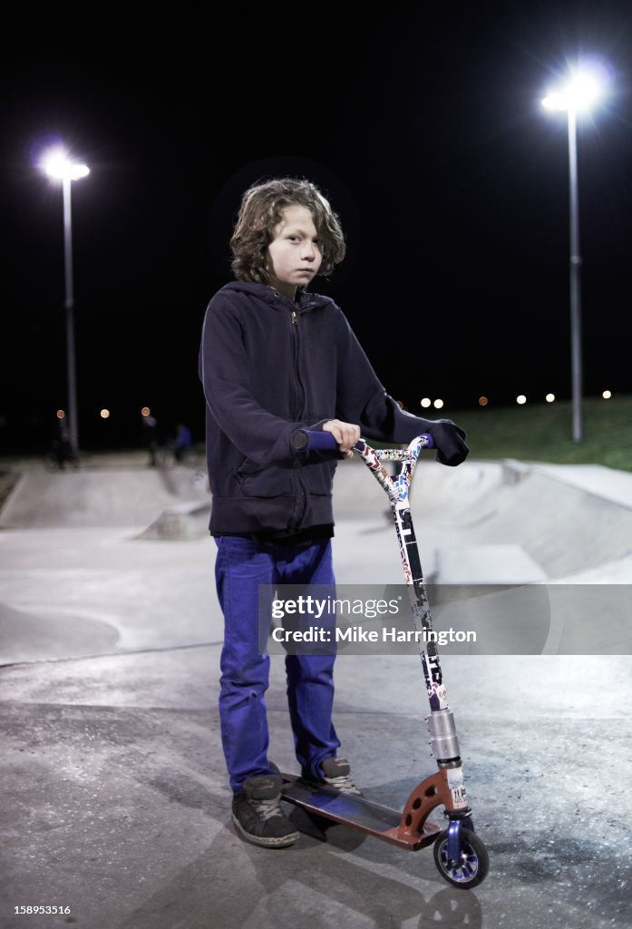 Boy looking straight to camera holding scooter