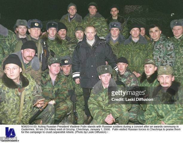 Acting Russian President Vladimir Putin stands with Russian soldiers during a concert after an awards ceremony in Gudermes, 30 km east of Grozny,...