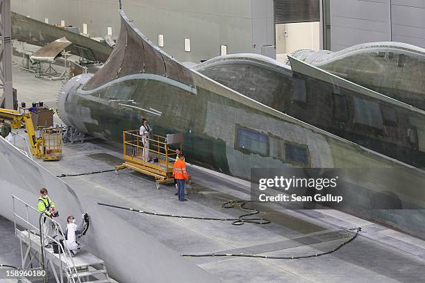 Workers prepare rotor blades for wind turbines at the Enercon wind turbine factory on January 4, 2013 in Aurich, Germany. Germany is invetsing...