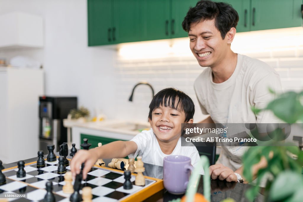 Young father teaching his son playing chess