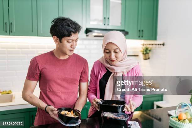 young husband and wife preparing food at home - banten stock pictures, royalty-free photos & images