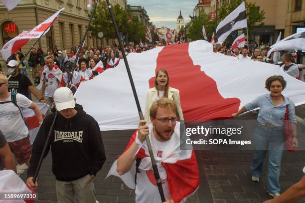 Demonstrators hold a huge white-red-white flag during the Belarusians' march on the third anniversary of the 2020 presidential election in Belarus....