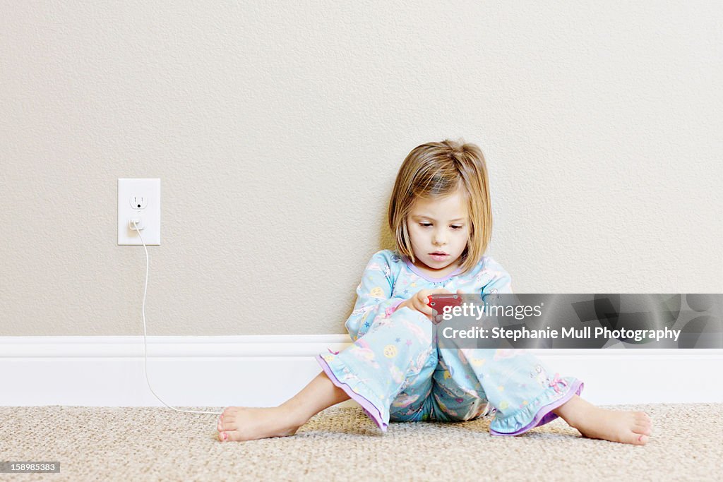 Girl Sitting Against Wall Playing on a Smart Phone