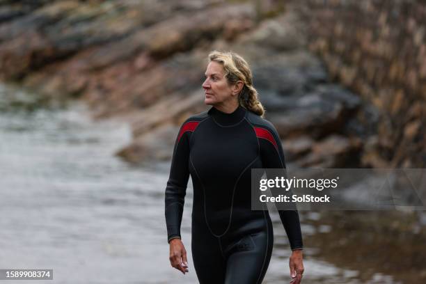 walking into shore after swimming - wetsuit stock pictures, royalty-free photos & images