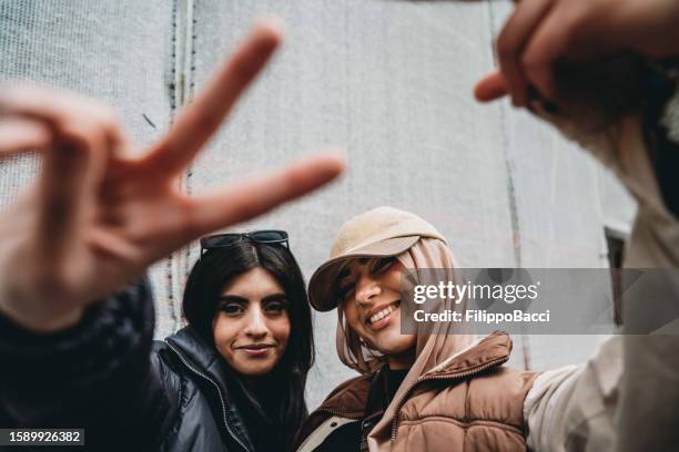 due giovani ragazze adulte stanno facendo gesti divertenti alla telecamera - celebrities in street foto e immagini stock