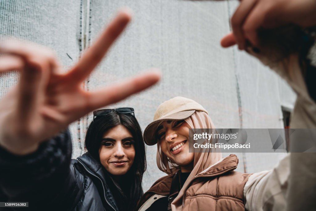 Two young adult girls are making funny gestures to the camera