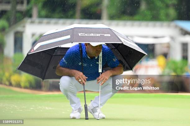 Gary Woodland of the United States lines up a putt under an umbrella on the 15th green during the first round of the Wyndham Championship at...