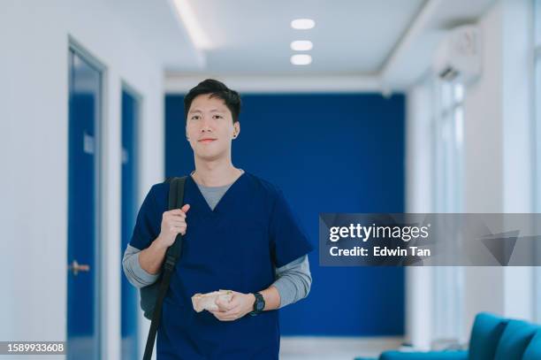 on the move asian chinese male nurse arriving for shift in hospital - doctor on the move stock pictures, royalty-free photos & images