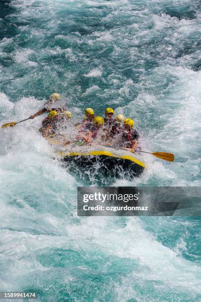 group of people as they ride the rapids while white water rafting in the waves of a river - white water rafting stock pictures, royalty-free photos & images